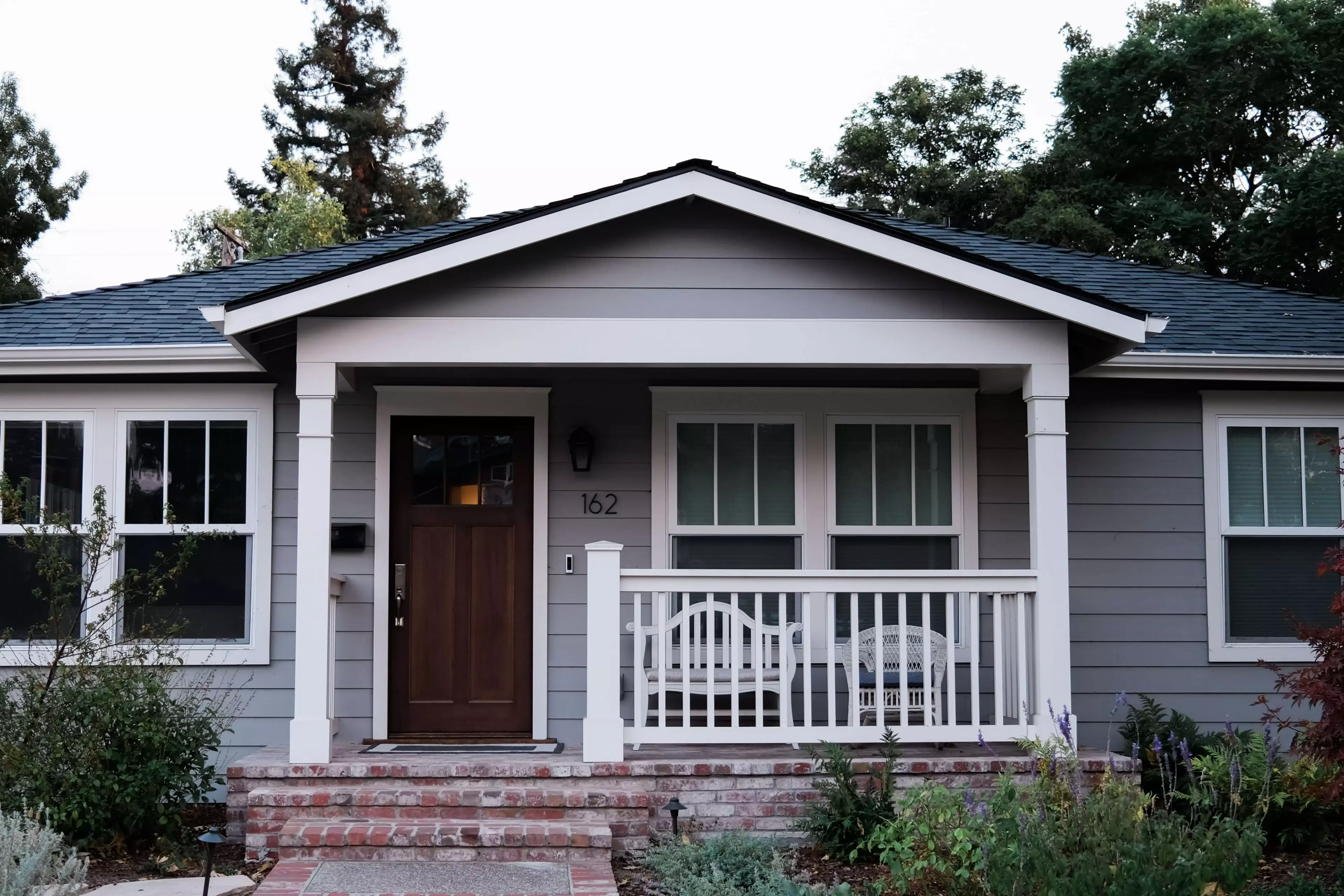 Craftsman styled house with gray siding, white trim, and blue roof